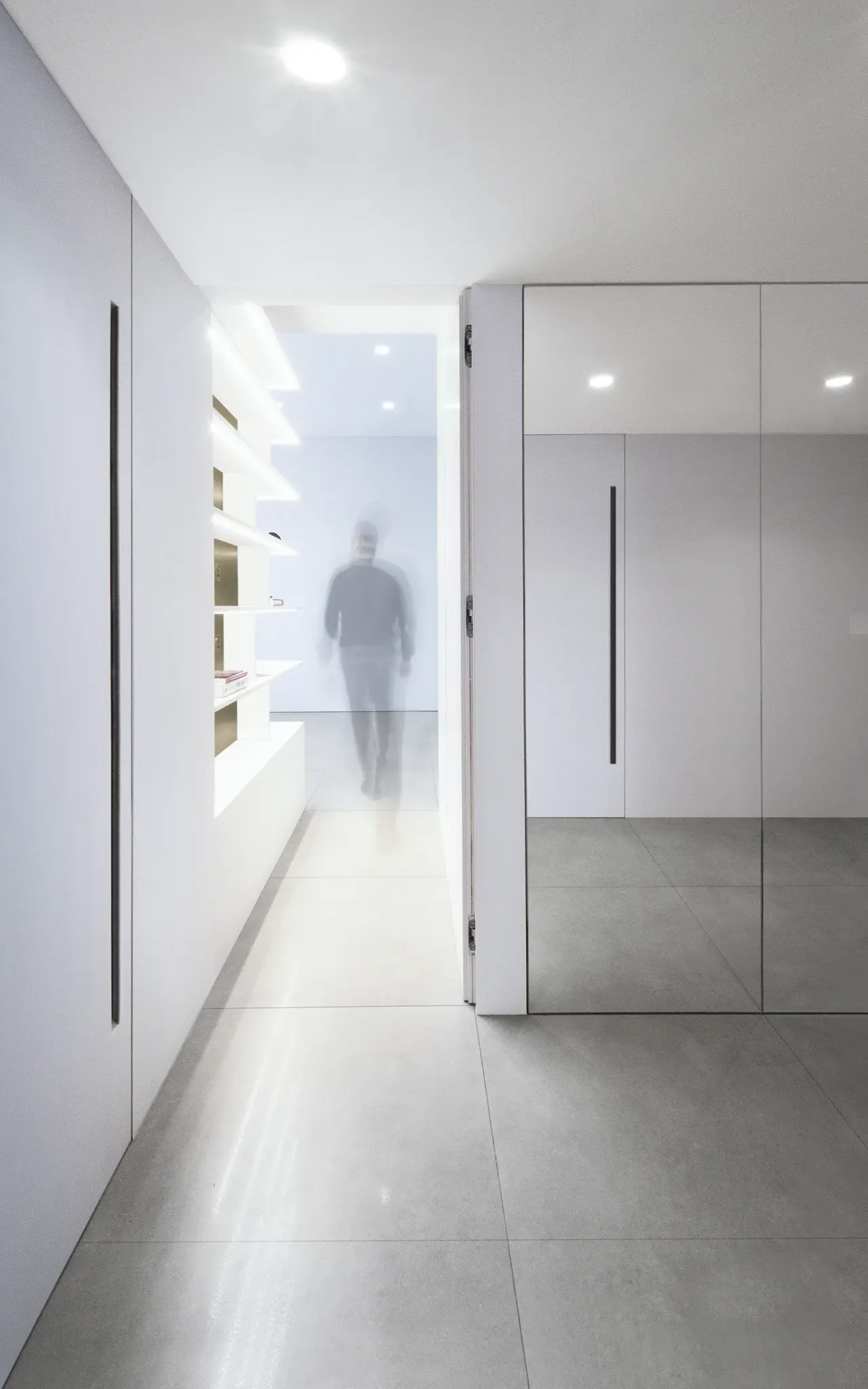 White corridor with full-height flush doors leading to a bright room