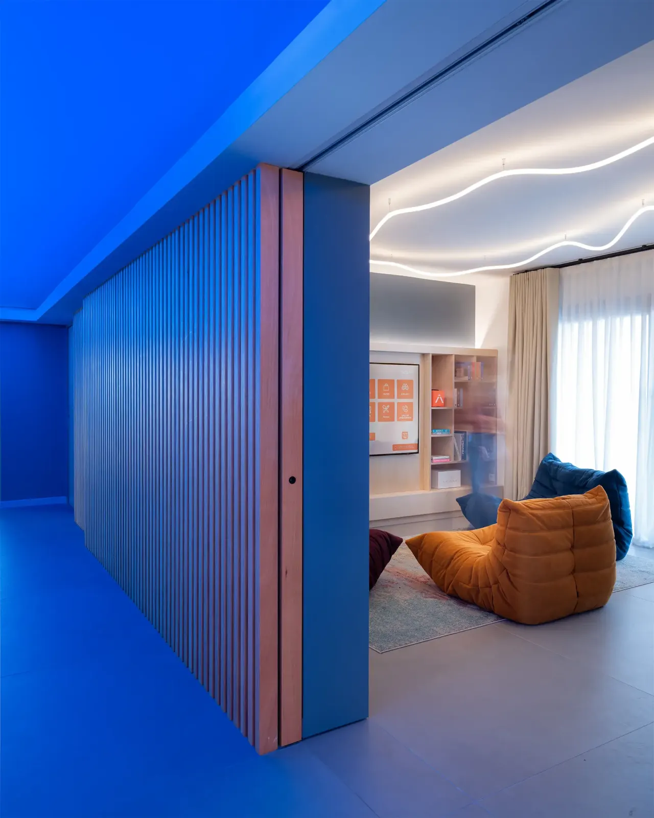 Blue corridor opening onto a lounge with colourful armchairs
