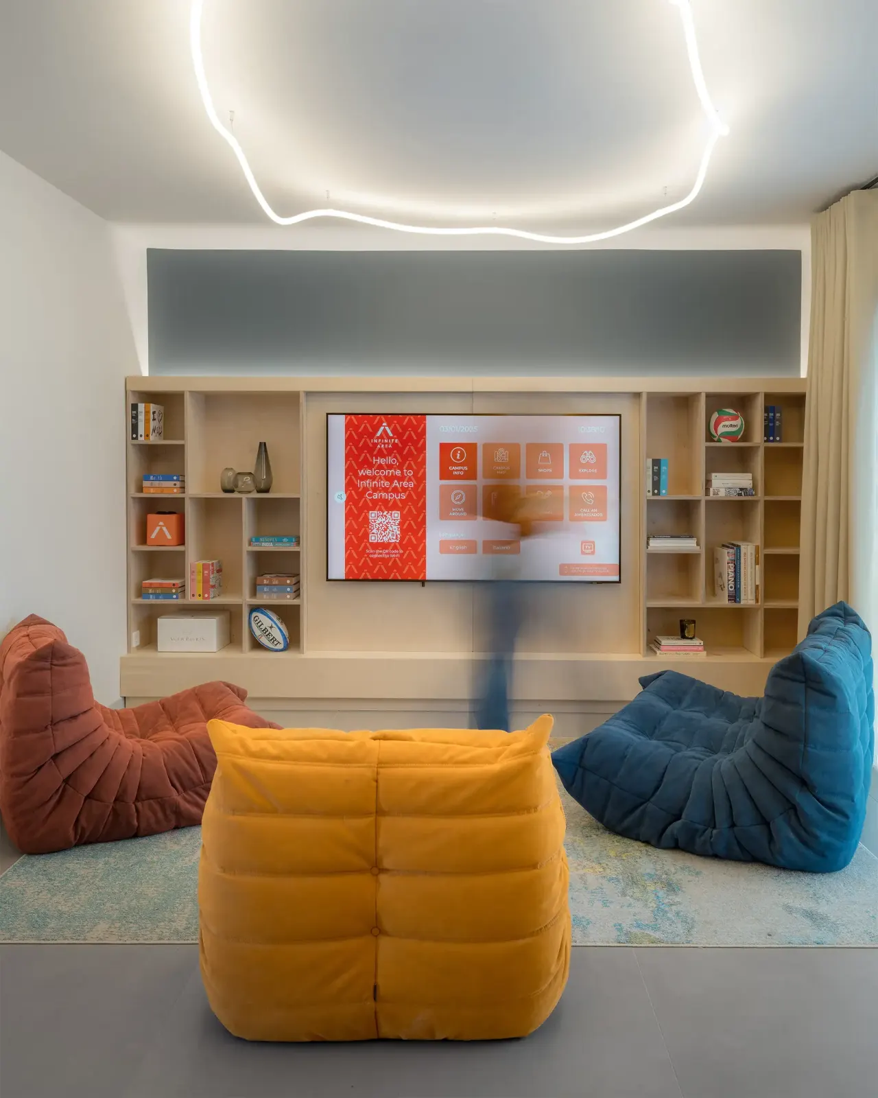 Lounge with orange, yellow and blue armchairs, shelving and a screen