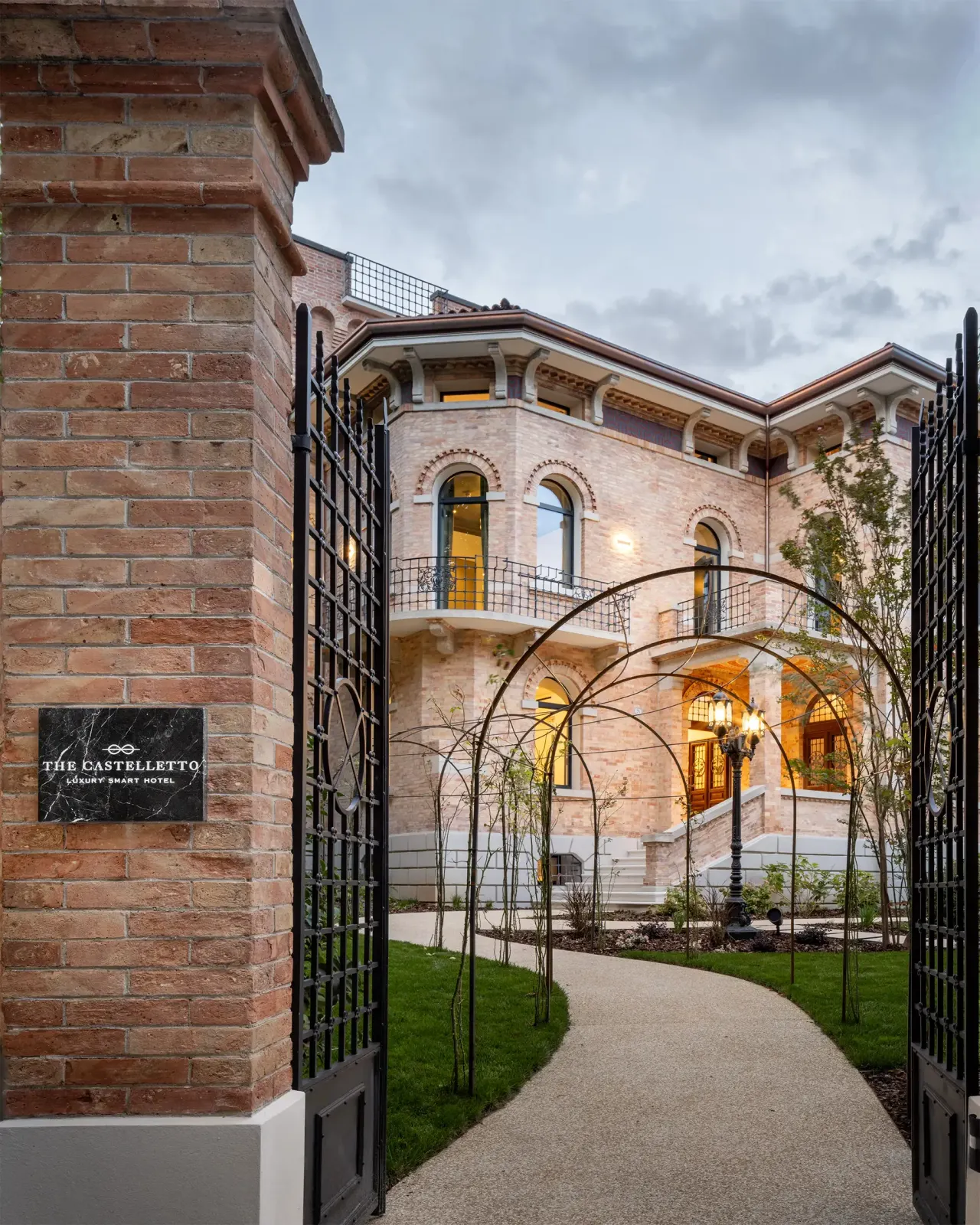 Garden gate and curved path leading to the restored brick villa