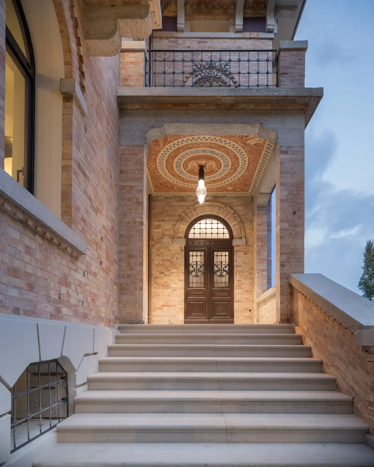 Stone steps up to the arched entrance under a decorated porch ceiling