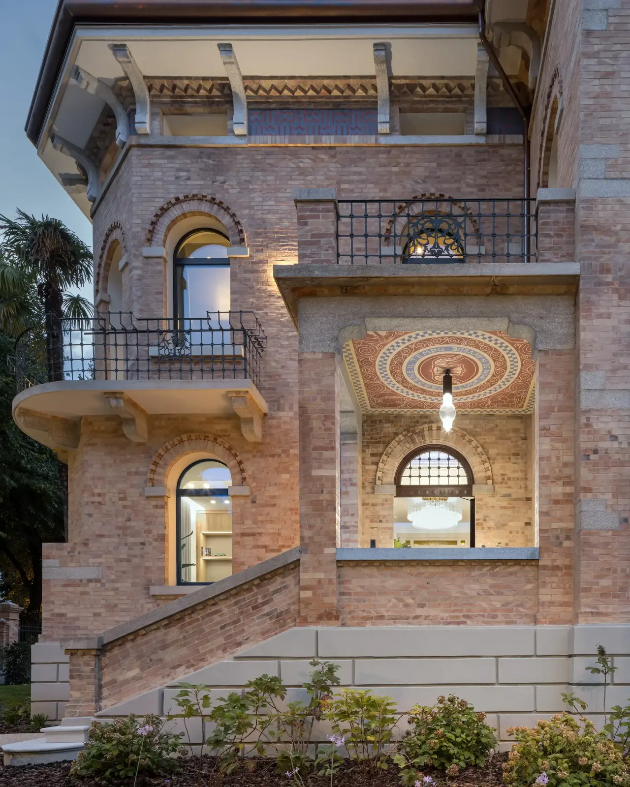 Brick facade with balconies, arched windows and a painted porch ceiling