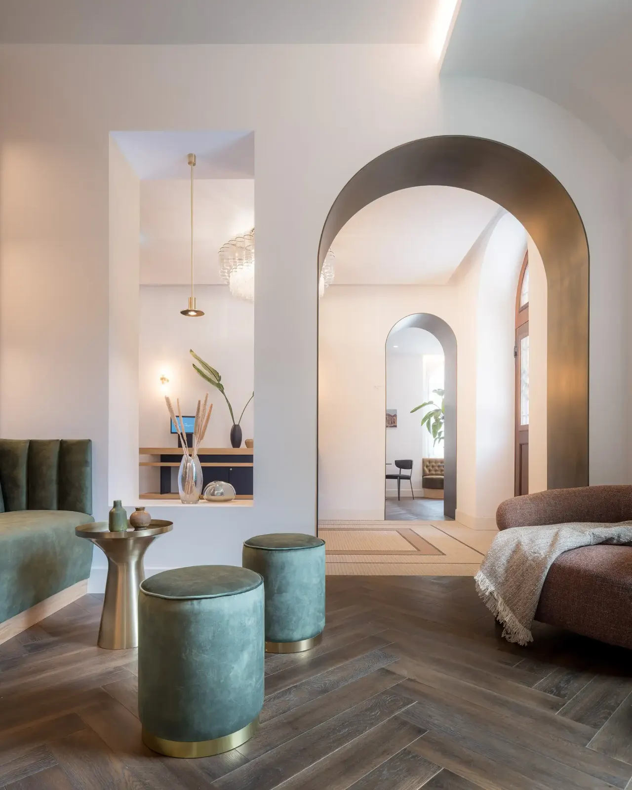 Guest room with herringbone floor, velvet stools and an arched opening