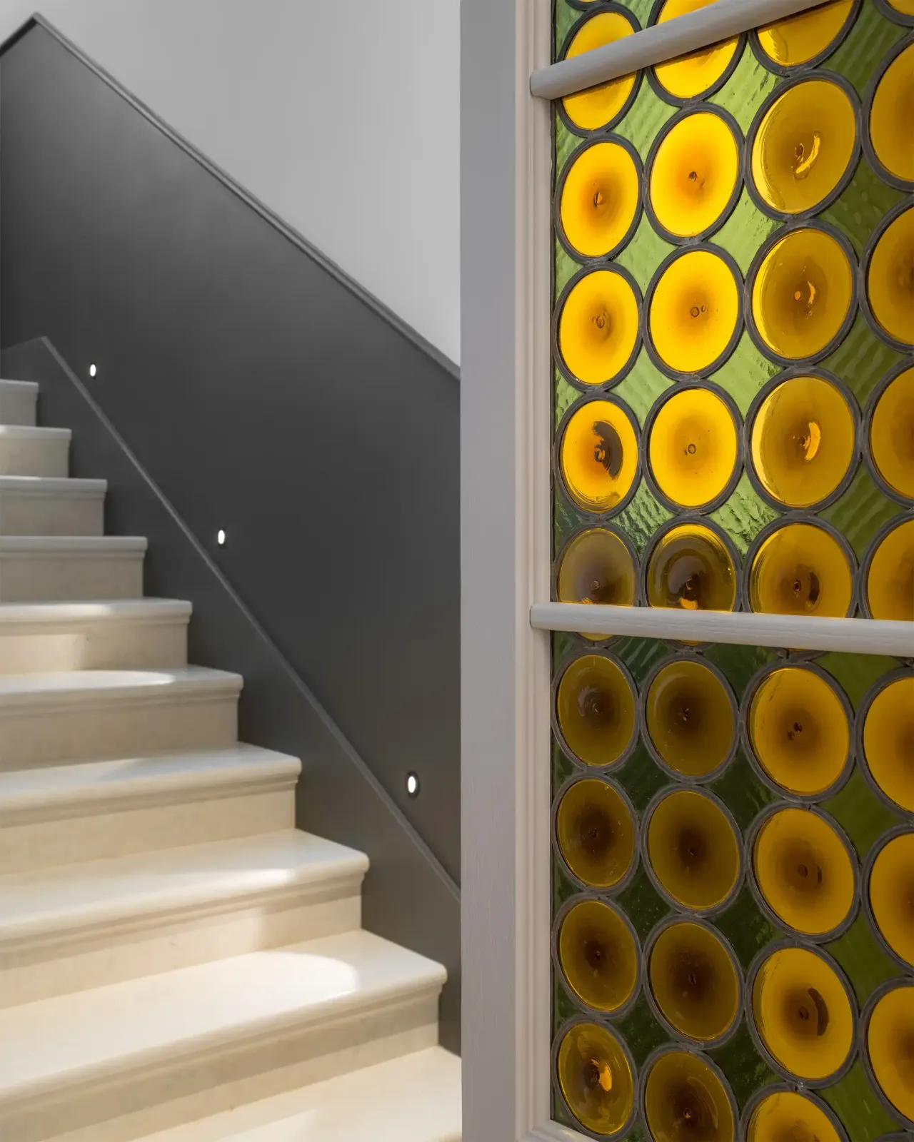 Stone staircase beside a wall of round coloured glass panels