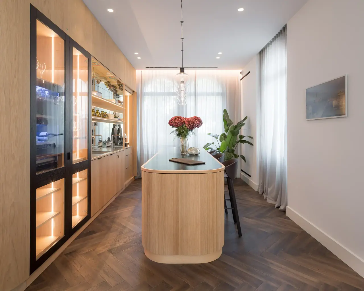 Kitchen with oak cabinetry, glass-fronted units and a rounded island