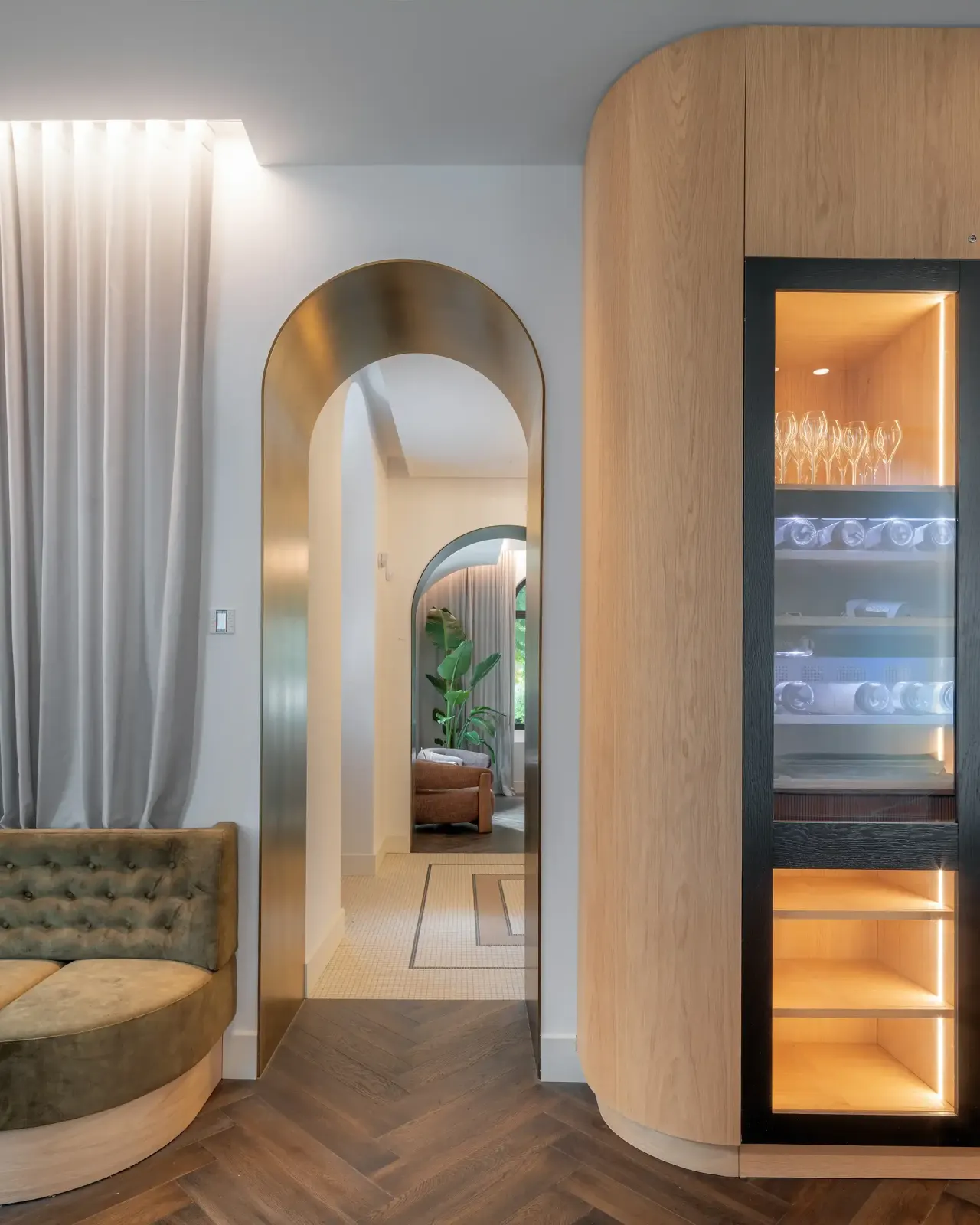 Arched doorway between a curved oak wall and an upholstered banquette