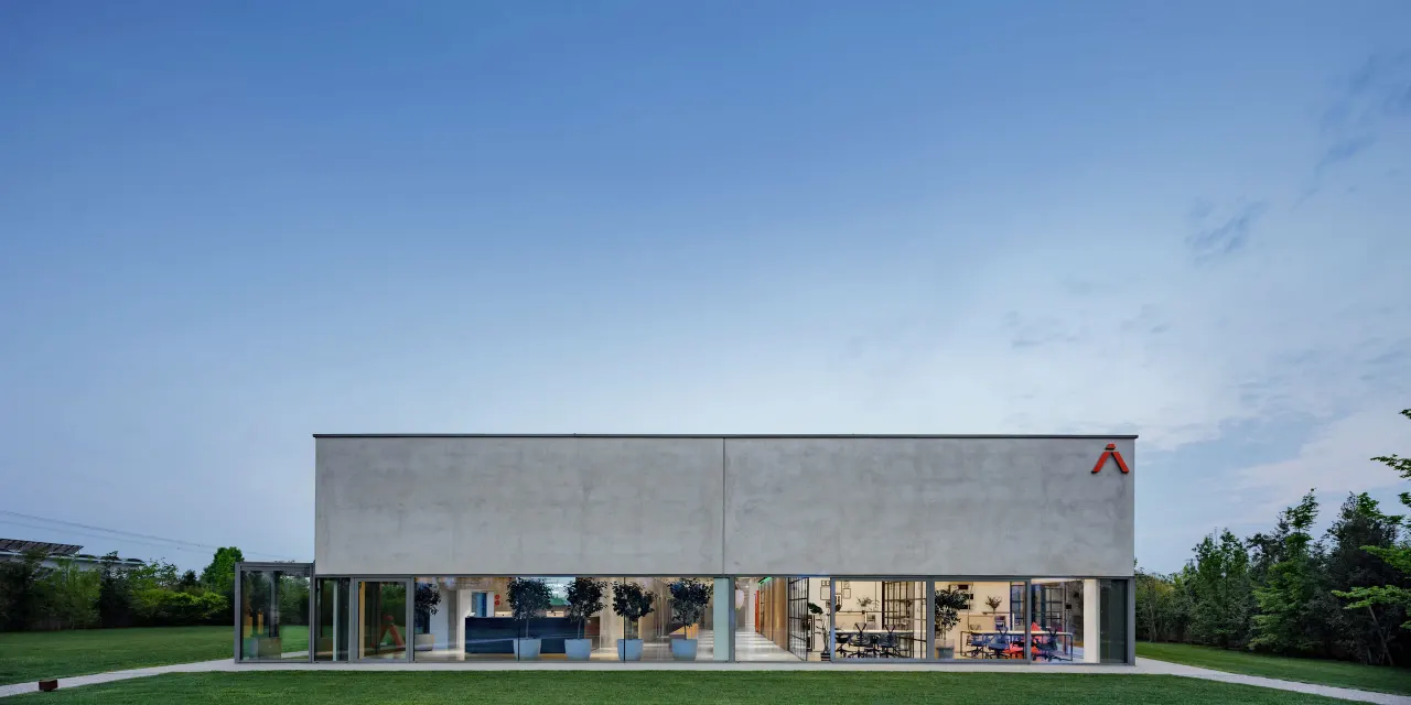The Hangar at dusk: a concrete volume above a fully glazed ground floor