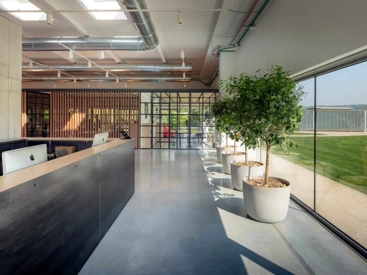 Reception desk and planted walkway along the glass wall