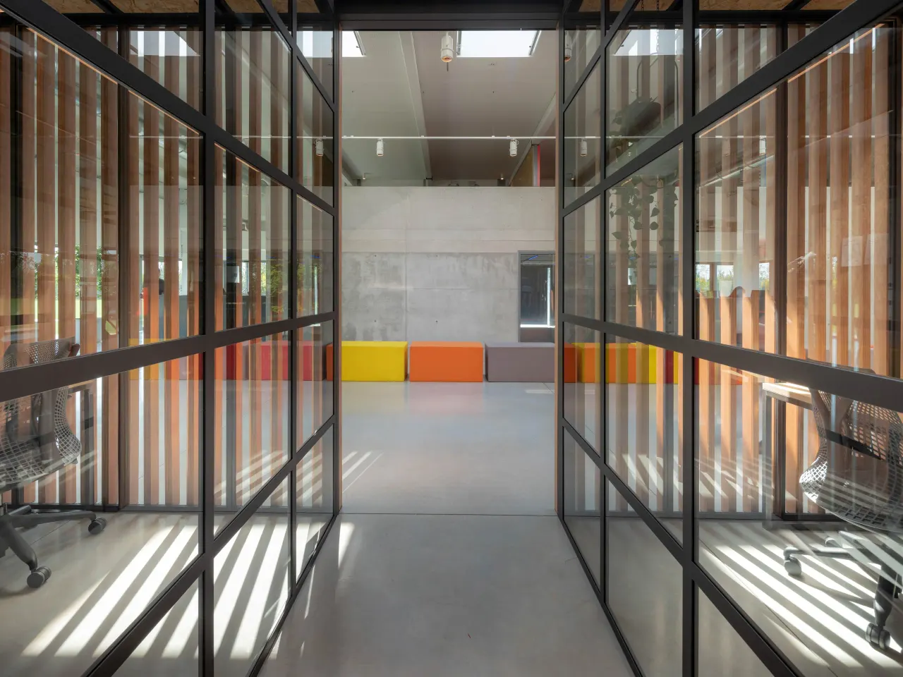 Black steel and glass partitions casting striped shadows on the floor