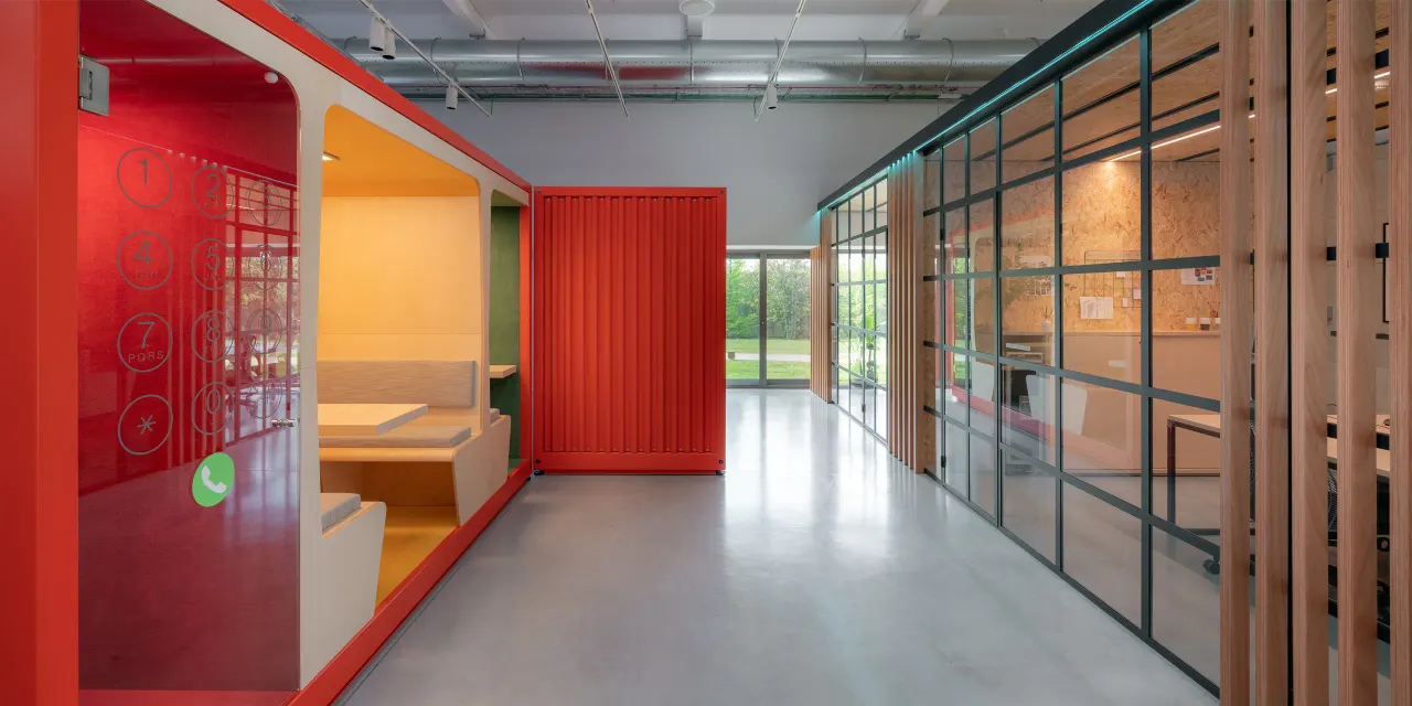 Red container meeting pod beside glazed offices