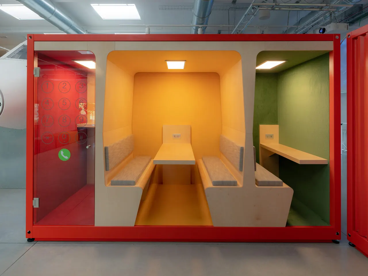 Red container converted into booths with yellow and green interiors