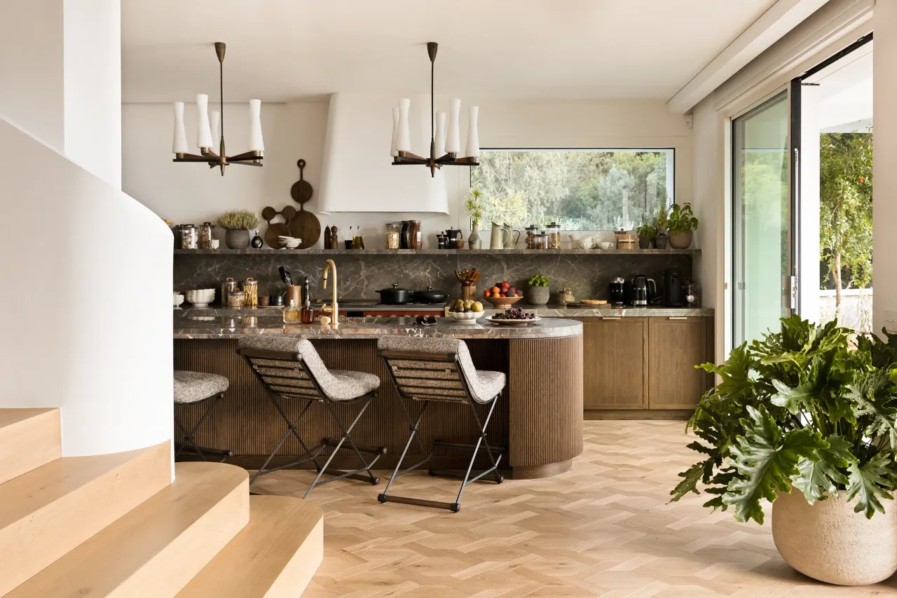 Kitchen with oak island, bar stools and a curved white staircase