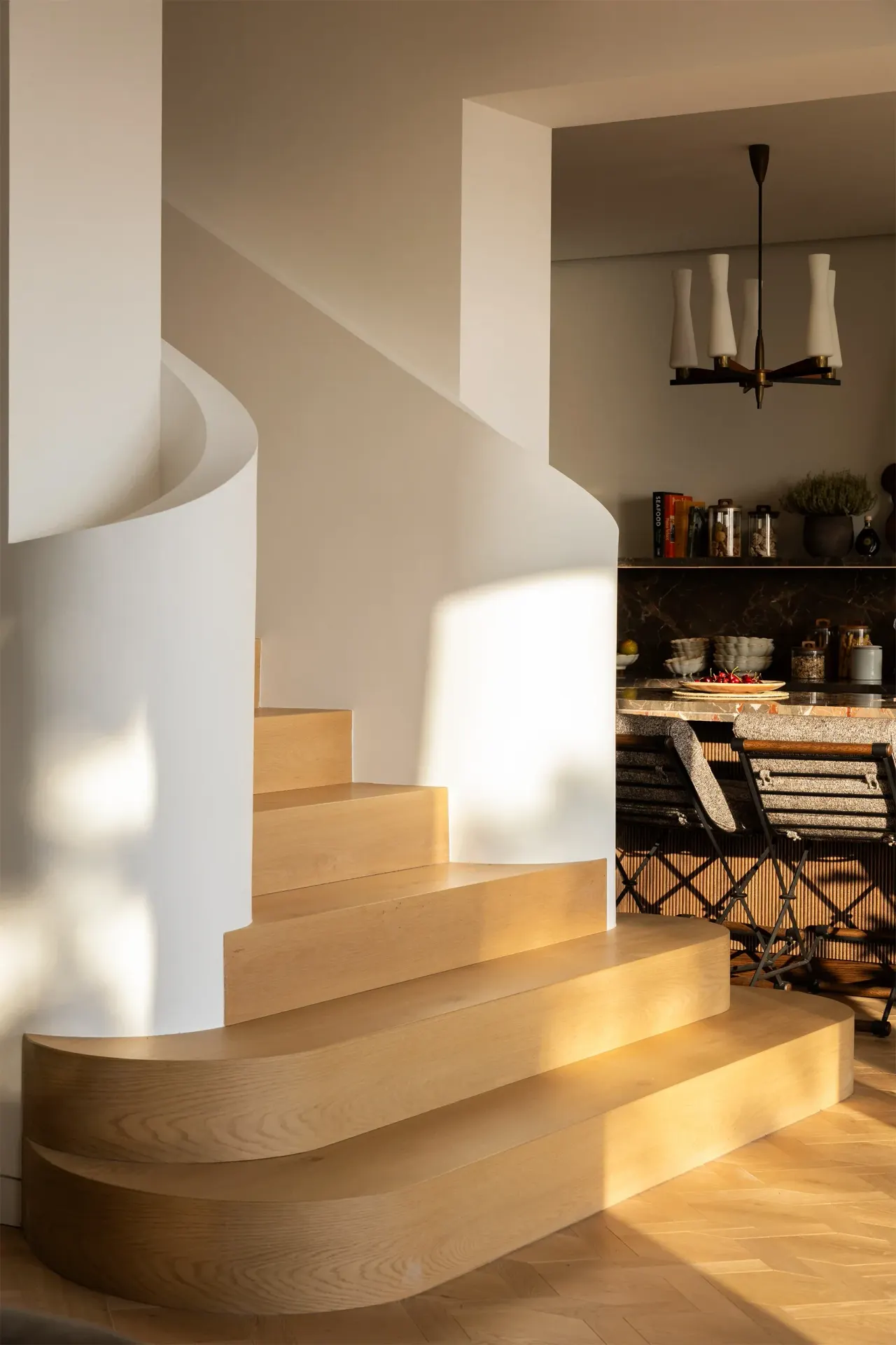 Curved white staircase with oak treads beside the kitchen
