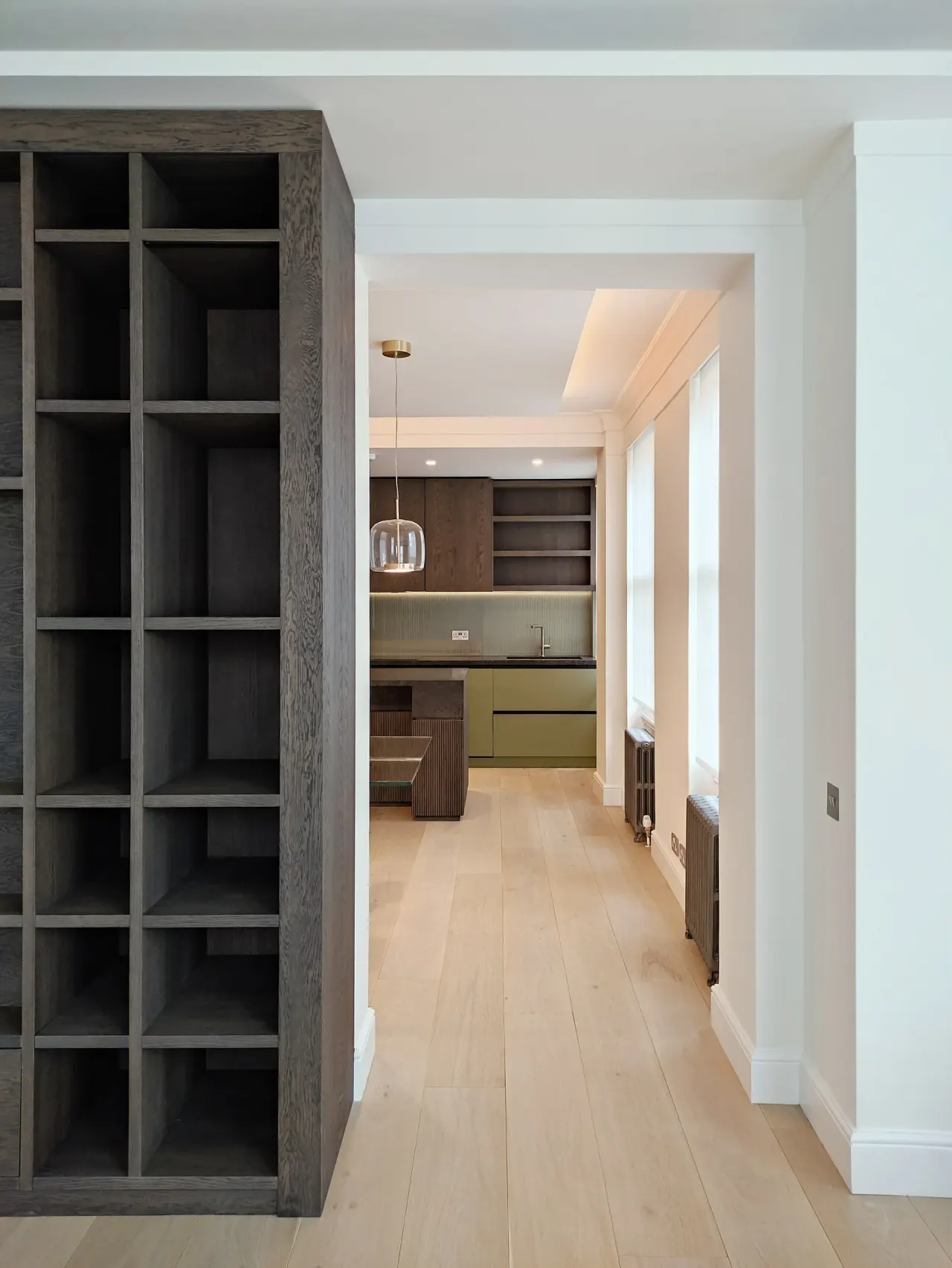 Dark oak shelving unit framing the view along the flat