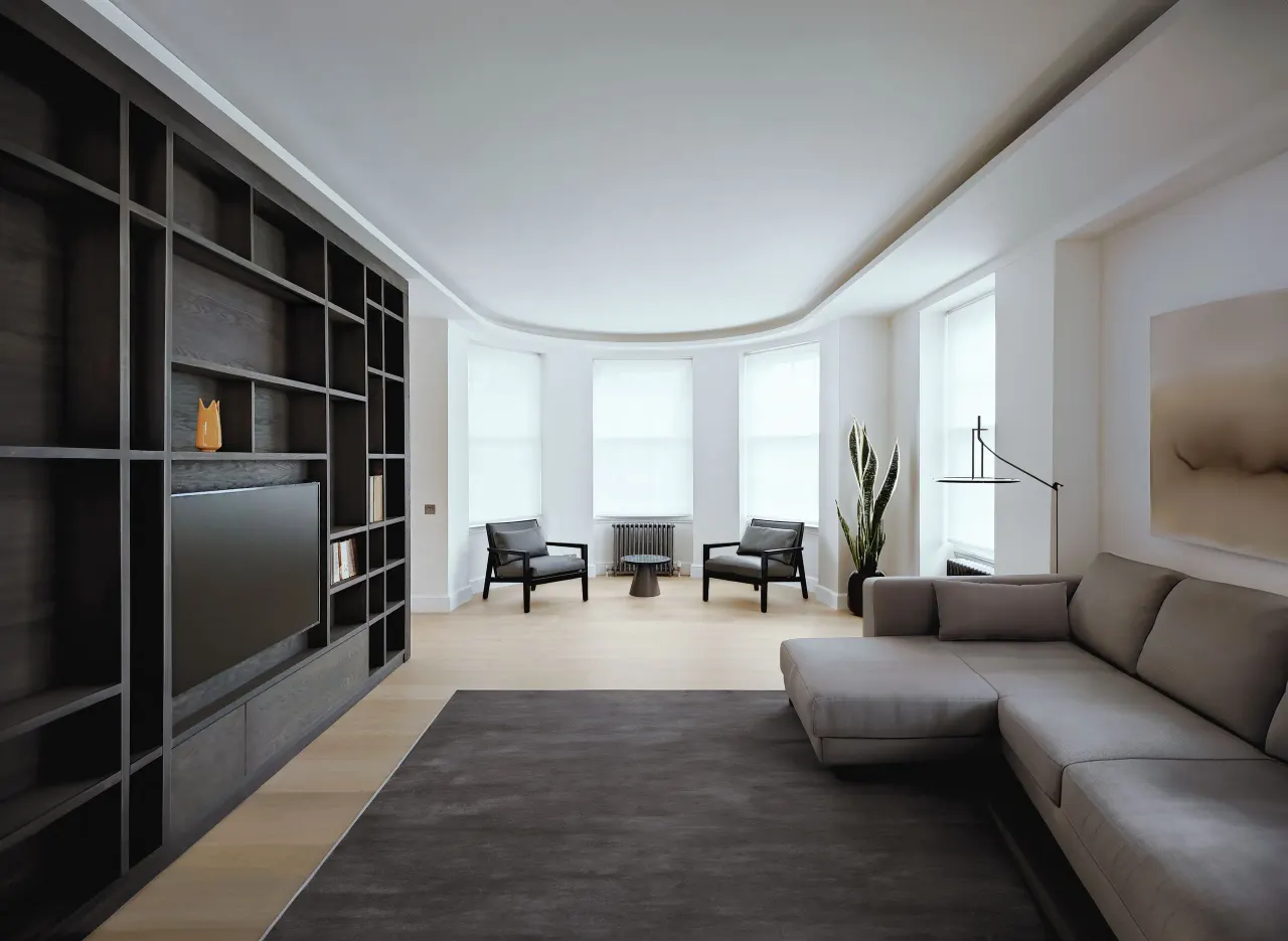 Living room with dark oak bookcase and TV wall, grey sofa and bay windows