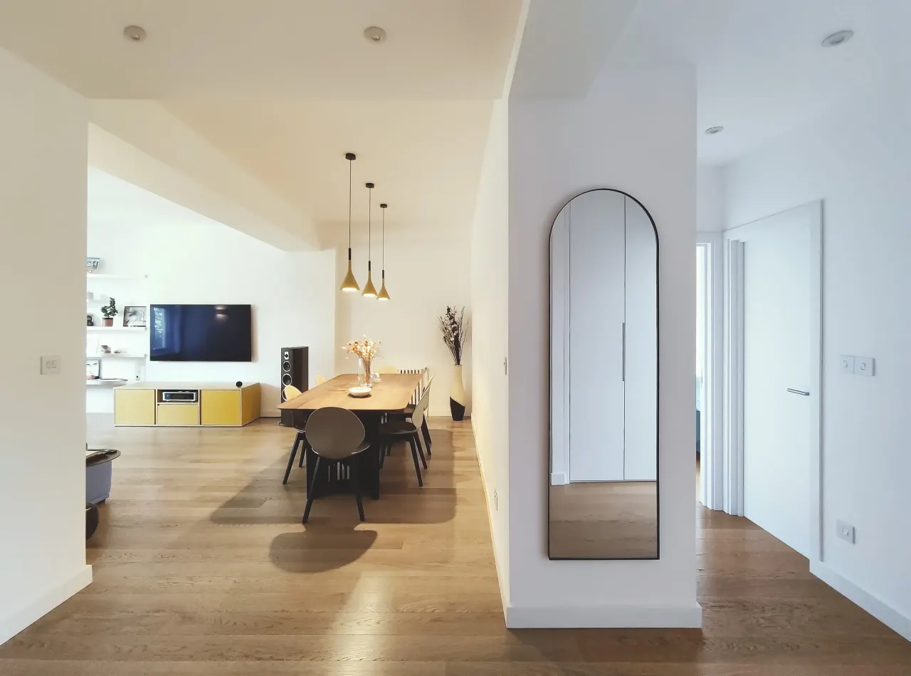 Open-plan living and dining room seen from the hallway with an arched mirror