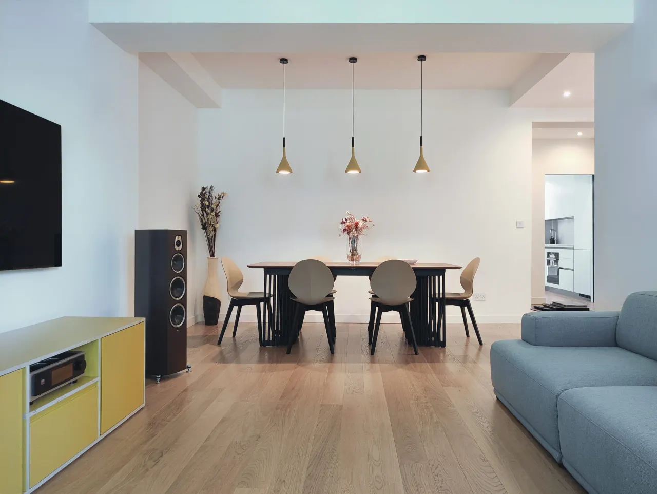 Dining table with pendant lights, blue sofa and yellow sideboard