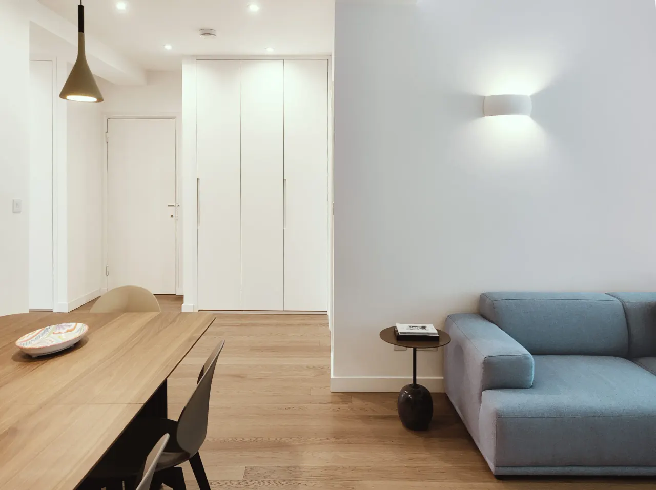 Blue sofa, oak table and white built-in wardrobes