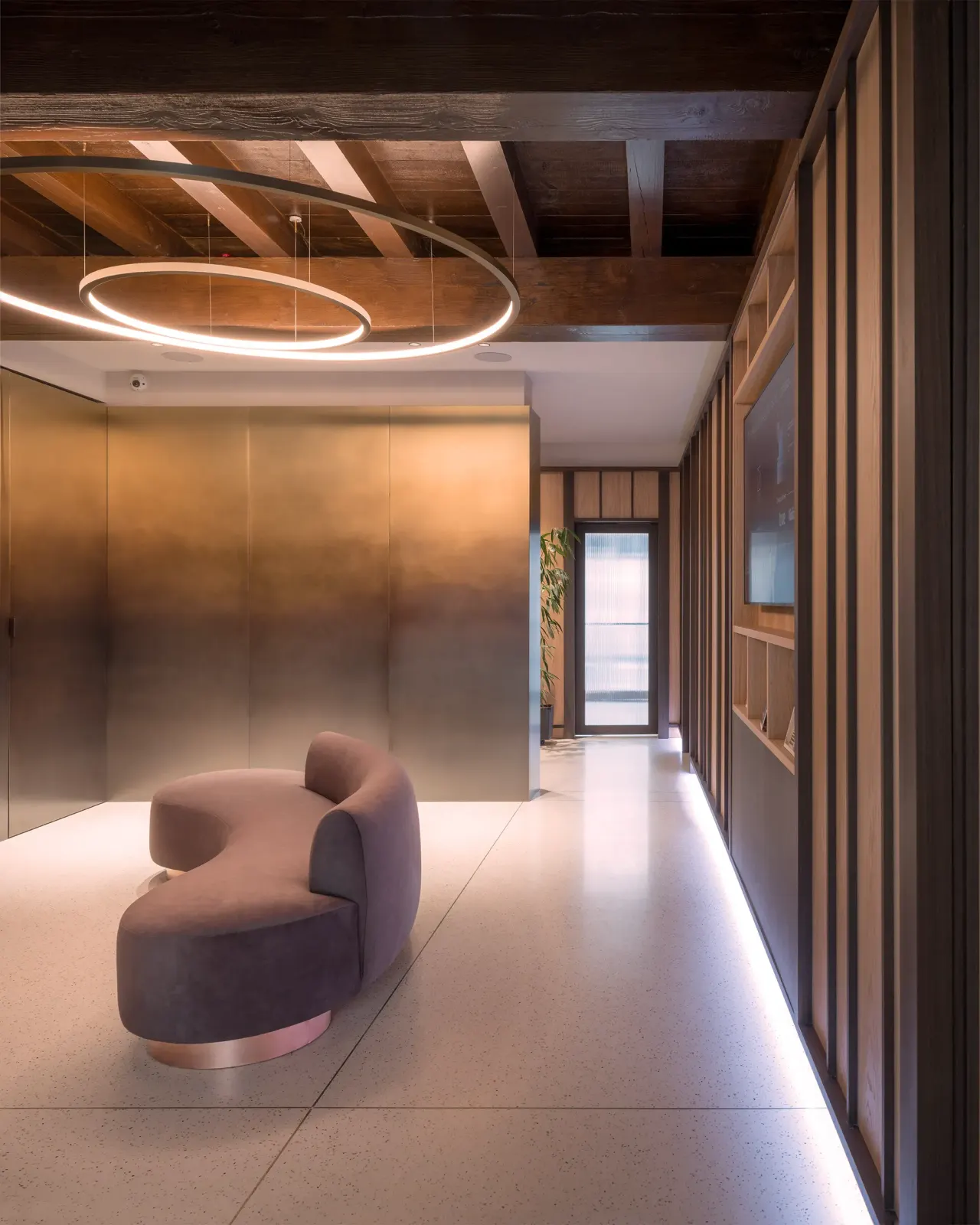 Reception with a curved sofa, bronze-toned walls and timber ceiling