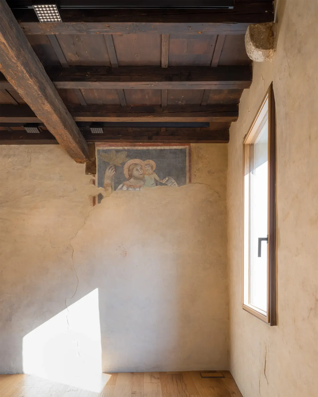 Room with timber beamed ceiling and a fragment of historic fresco
