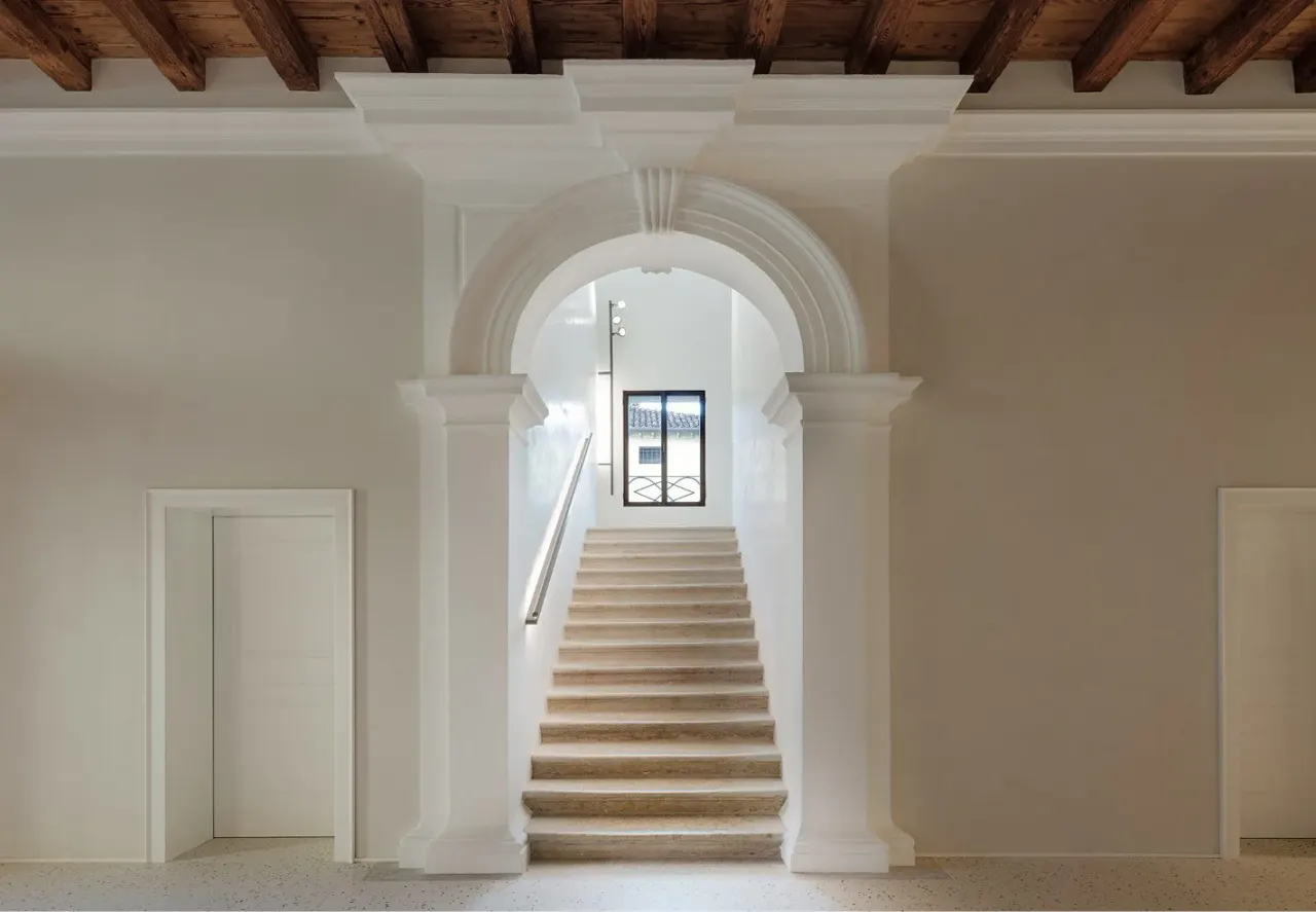 Entrance hall with stone staircase under a classical arch