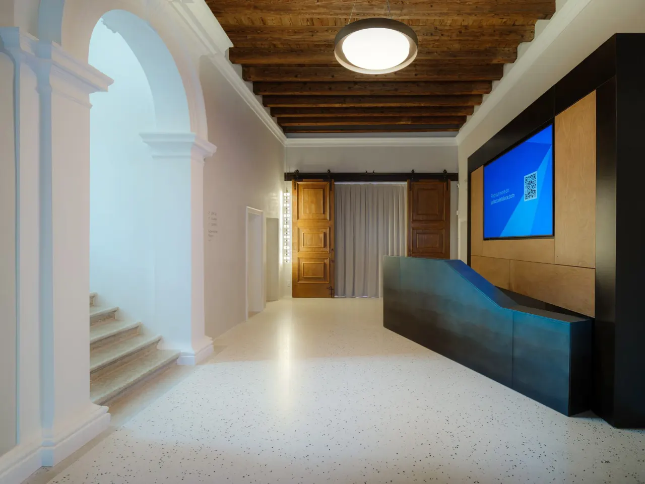 Reception desk and screen beside the staircase under a timber ceiling