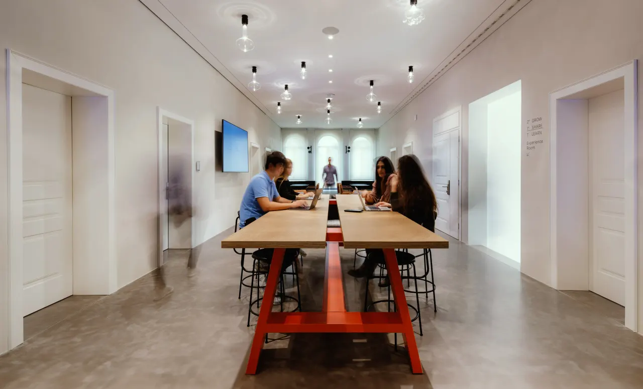 Meeting room with a long red-legged table and pendant lights