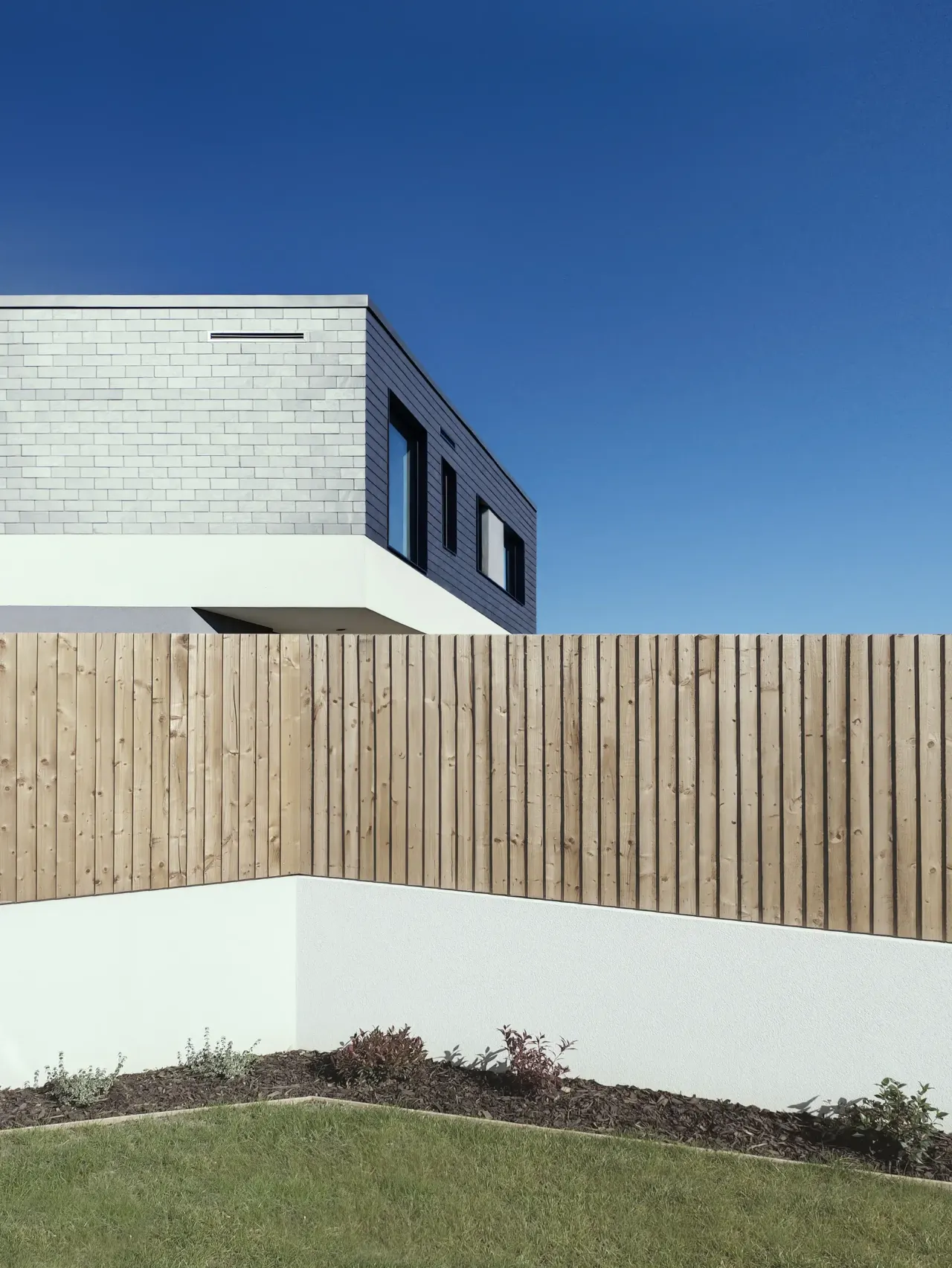 Corner of the slate-clad volume above a timber fence