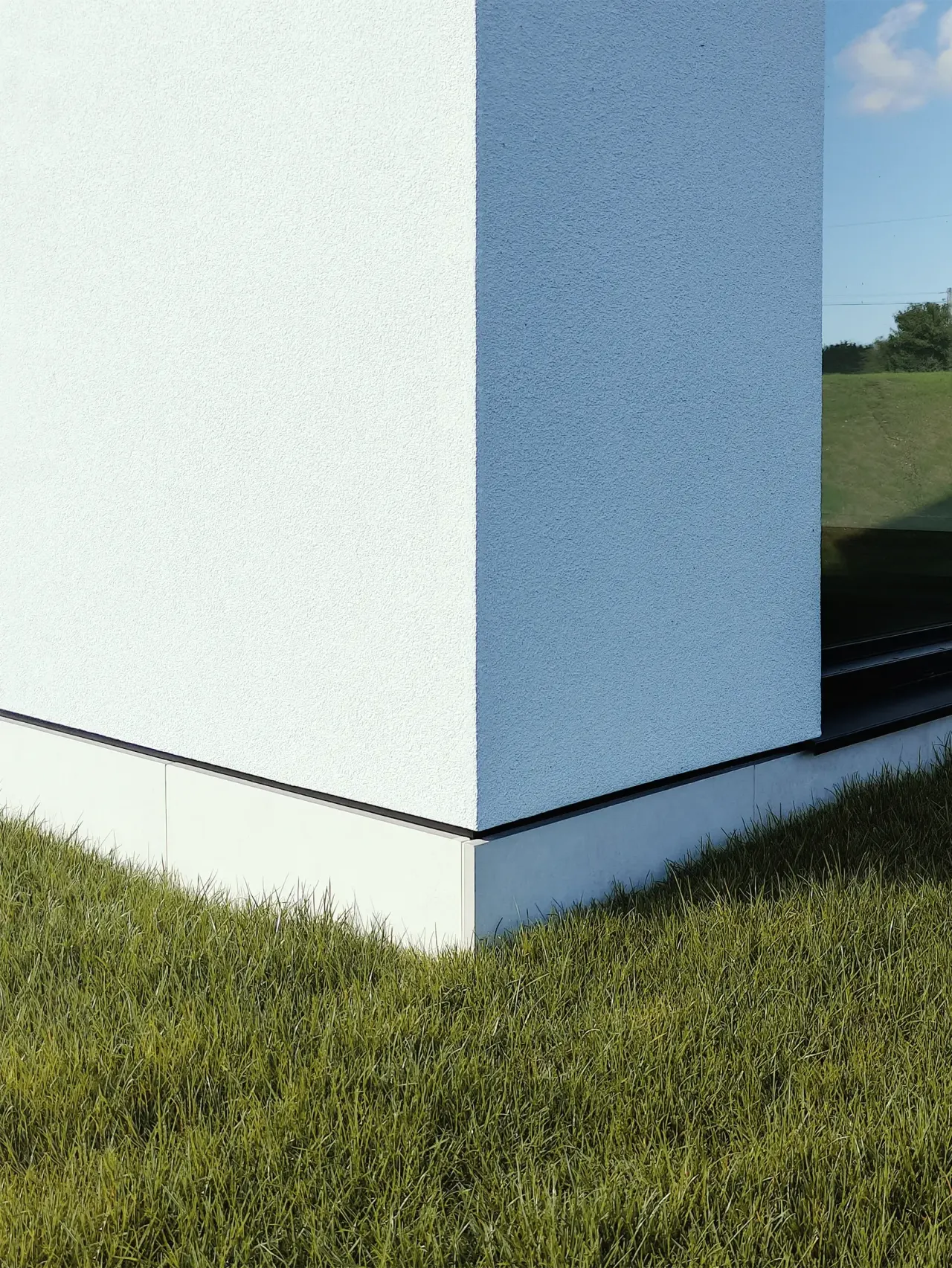 Detail of the white rendered corner meeting the lawn