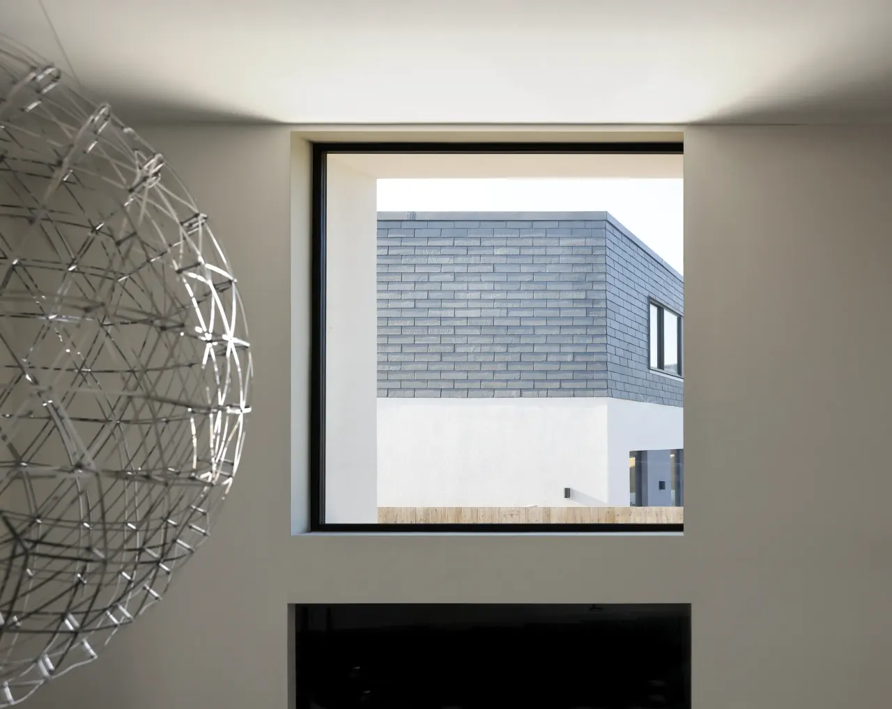 Interior view through a square window to the slate-clad volume